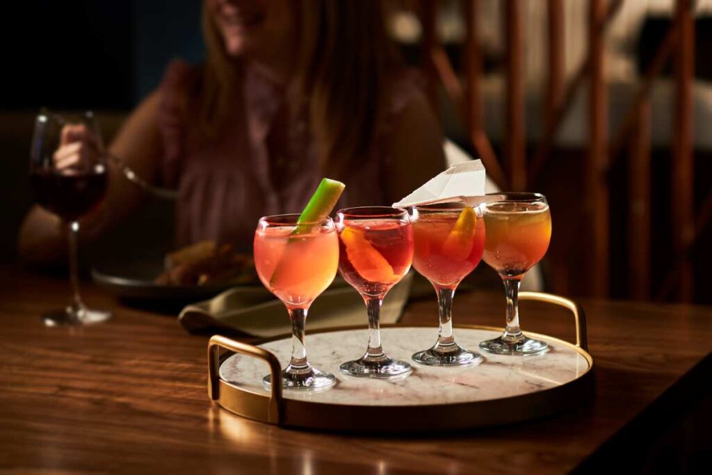 four different cocktails lined up on a tray